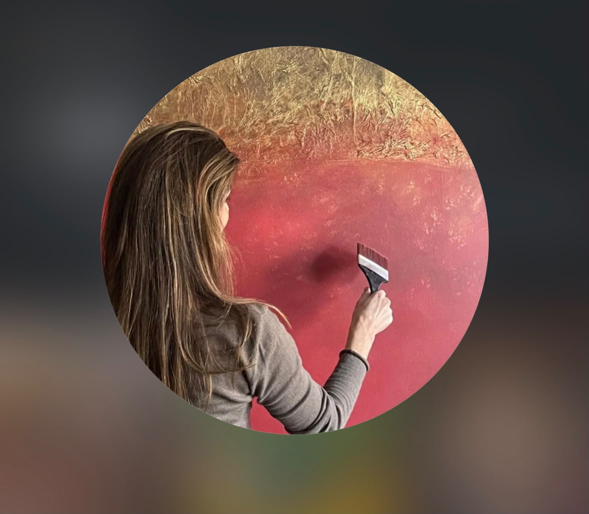Ilka working on a red and gold circular canvas